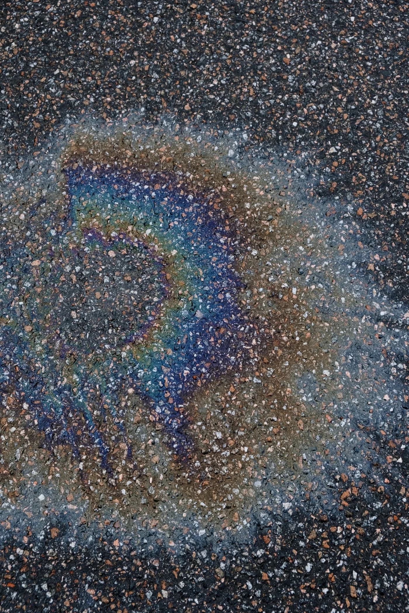 Gasoline and fuel rainbow sheen on pavement near a local site